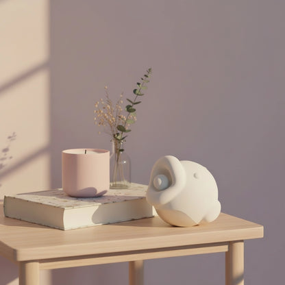 fish-shaped vibrator placed on a bedside table surrounded by candles, books, and soft morning light
