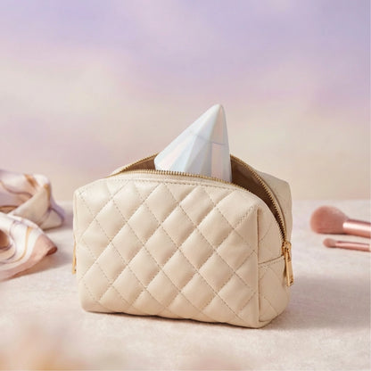 The pearl-white diamond-shaped wellness device nestled inside a small, high-quality makeup pouch against a soft beige background. The image emphasizes its discreet portability and elegant design, showing how it blends seamlessly into a personal care routine