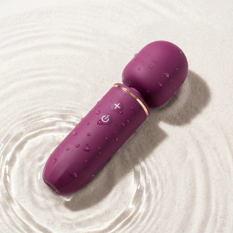 Massager in water droplets, highlighting its IPX7 waterproof design for safe cleaning and shower use.