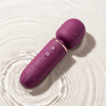 Massager in water droplets, highlighting its IPX7 waterproof design for safe cleaning and shower use.