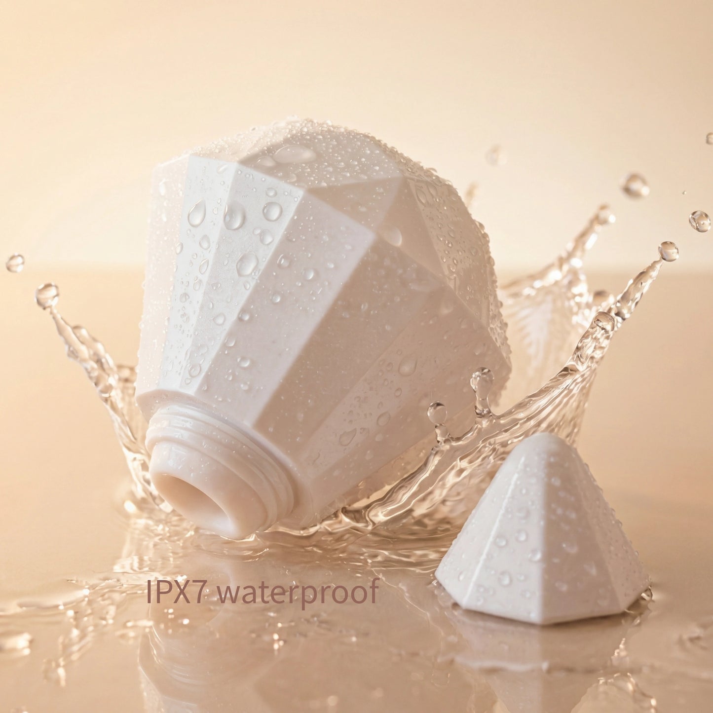 Pearl-white diamond-shaped wellness device displayed with clear water droplets on a soft beige background, representing waterproof performance and premium hygiene

