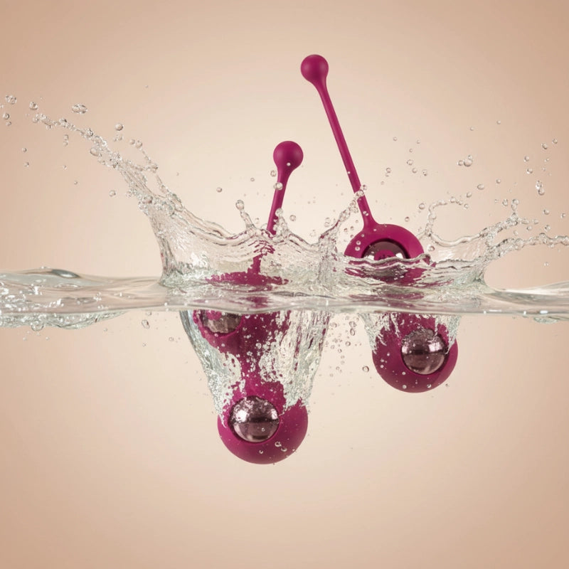 The wine-red 2-in-1 Kegel ball resting submerged in clear water, visually certifying its complete IPX7 waterproof rating for worry-free cleaning, shower use, and total hygiene control.
