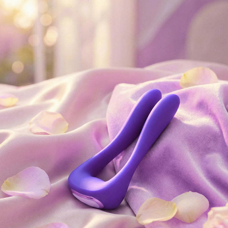 The wellness device resting on soft satin fabric with warm diffused lighting and feminine decorative elements.