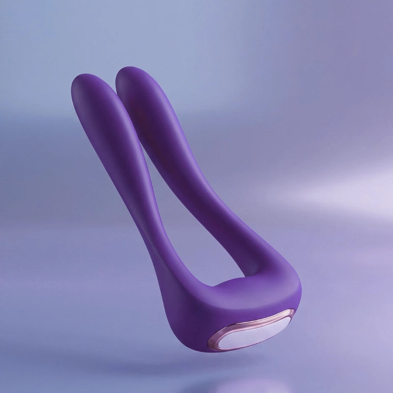 Elegant rose-purple silicone wellness device floating in soft diffused studio light against a white-to-blush gradient background.