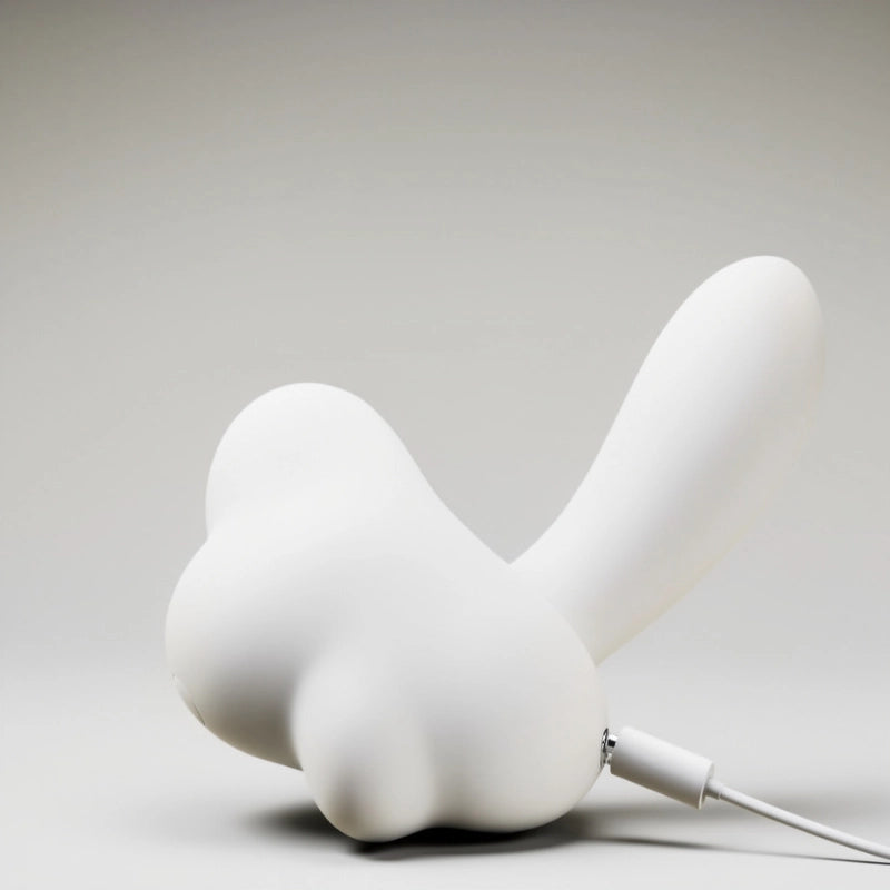 Lifestyle image of the mushroom-shaped dual-action pleasure toy, shown from a front view while connected to its dedicated charging cable. The photo highlights the convenient magnetic charging port, which seamlessly attaches for hassle-free powering and enhances the product's waterproof integrity by eliminating exposed ports.