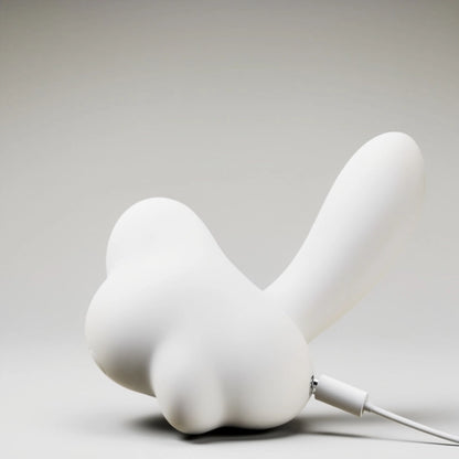 Lifestyle image of the mushroom-shaped dual-action pleasure toy, shown from a front view while connected to its dedicated charging cable. The photo highlights the convenient magnetic charging port, which seamlessly attaches for hassle-free powering and enhances the product's waterproof integrity by eliminating exposed ports.